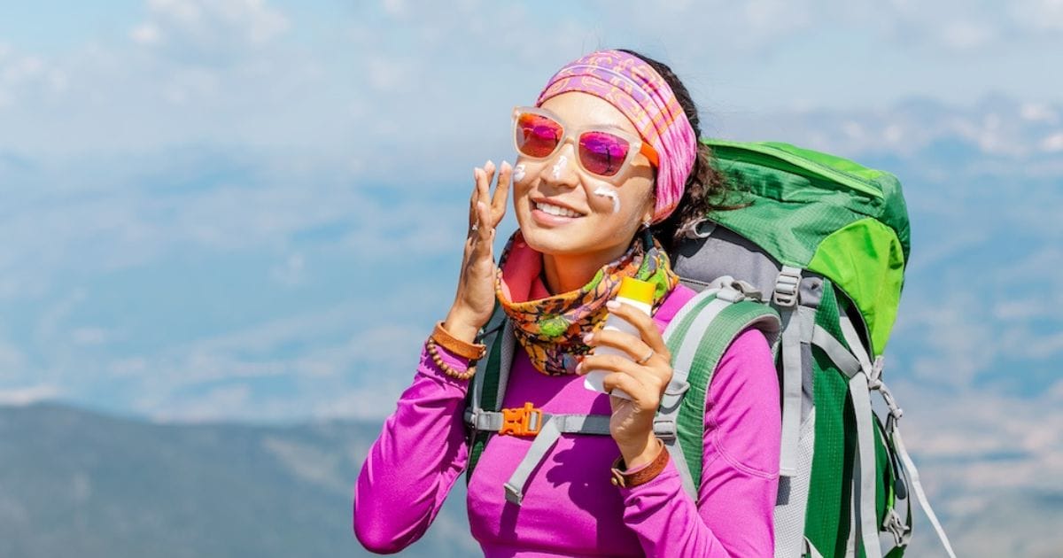 ragazza mette la crema solare sul viso in montagna