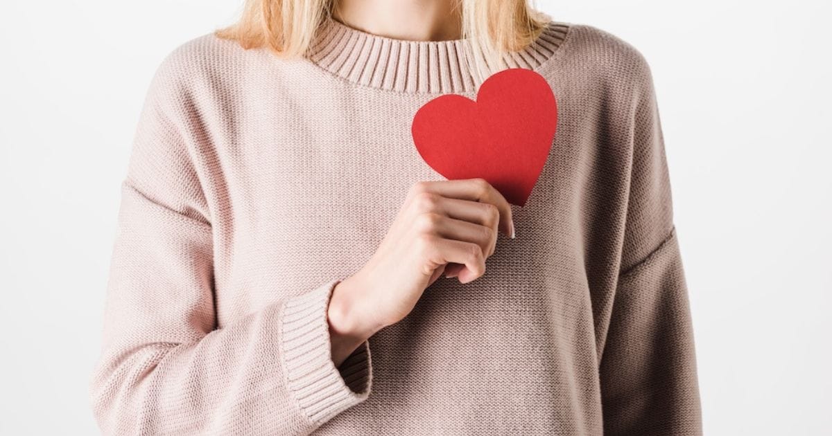 ragazza con un cuore rosso di carta in mano, a simbolo del colesterolo da abbassare
