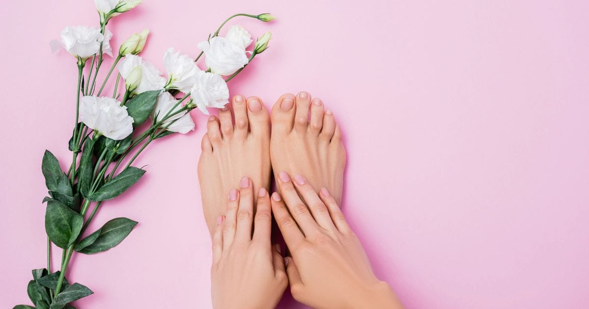 mani e piedi con unghie belle e sane, accanto un ramo con dei fiori bianchi