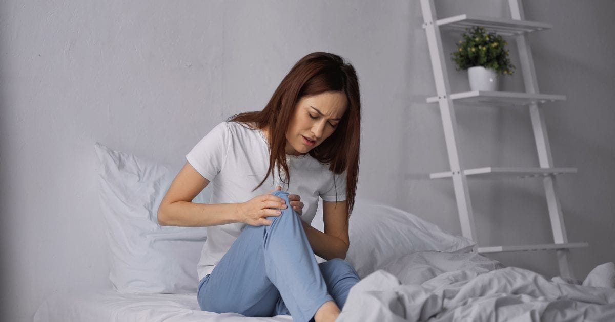 donna si tiene tra le mani le gambe doloranti