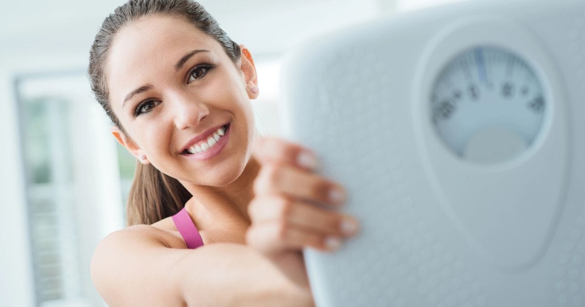 donna felice con bilancia dopo avere assunto gli integratori alimentari per ingrassare